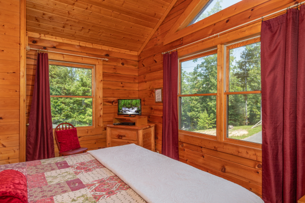 Dresser, TV, chair, and lots of natural light in a bedroom at Majestic Mountain, a 4 bedroom cabin rental located in Pigeon Forge 