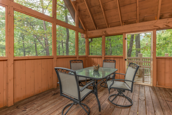 Dining space for four on a screened deck at Yes, Deer, a 2 bedroom cabin rental located in Pigeon Forge