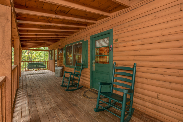 Green rocking chairs on a covered porch at Yes, Deer, a 2 bedroom cabin rental located in Pigeon Forge