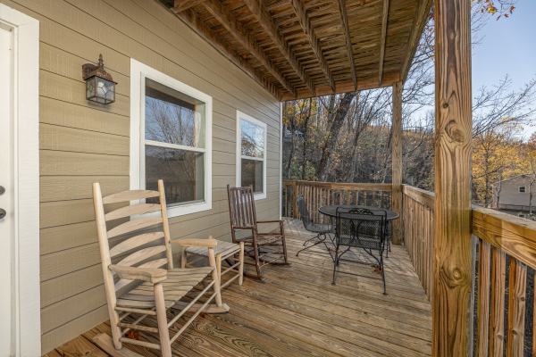 Rocking chairs and dining set on the deck at Le Bear Chalet, a 7 bedroom cabin rental located in Gatlinburg