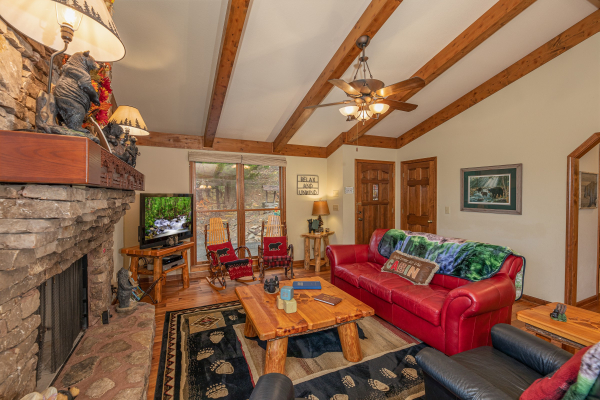 Living room with fireplace, TV, and red sofa at Lazy Bear Retreat, a 4 bedroom cabin rental located in Pigeon Forge
