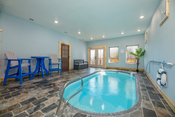 Indoor pool, table with chairs, and bench in the pool area at Pinot Splash, a 4 bedroom cabin rental located in Gatlinburg