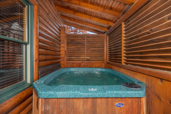 Hot tub with privacy fence on a covered deck at Loving Every Minute, a 5 bedroom cabin rental located in Pigeon Forge