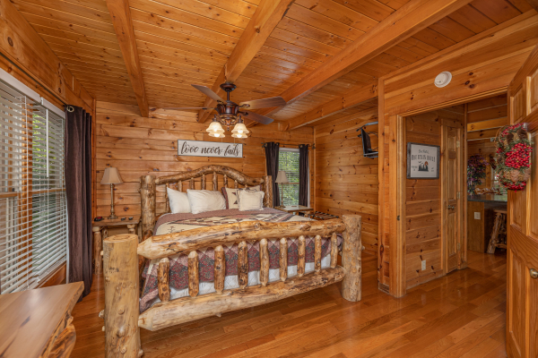 Bedroom with a king log bed, two night stands, and lamps at Logged Inn, a 3 bedroom cabin rental located in Pigeon Forge