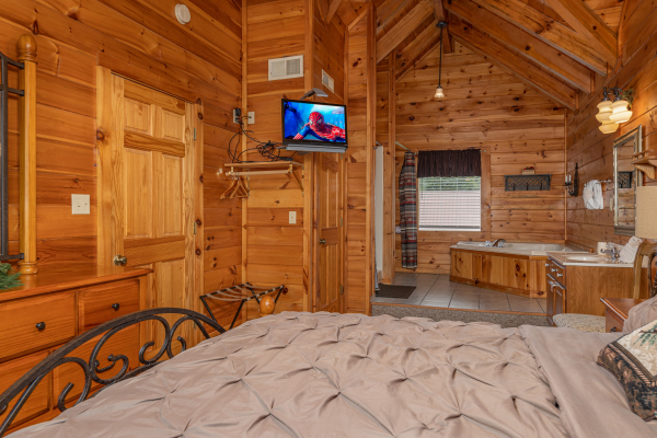 Dresser, TV, and en suite open bath with jacuzzi at Logged Inn, a 3 bedroom cabin rental located in Pigeon Forge