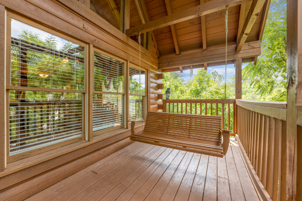 Swing on a covered deck at Logged Inn, a 3 bedroom cabin rental located in Pigeon Forge