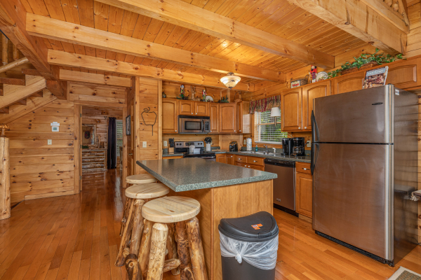 Kitchen with island seating for three and stainless appliances at Logged Inn, a 3 bedroom cabin rental located in Pigeon Forge