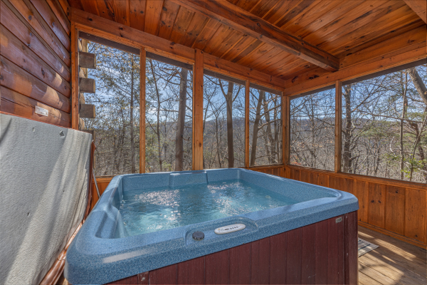Hot tub on a screened porch at Moonlit Pines, a 2 bedroom cabin rental located in Pigeon Forge