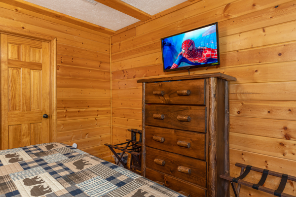 Dresser, two luggage racks, and TV in the bedroom at Pool Side Lodge, a 6 bedroom cabin rental located in Pigeon Forge