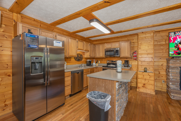Kitchen with stainless appliances and a breakfast bar at Pool Side Lodge, a 6 bedroom cabin rental located in Pigeon Forge