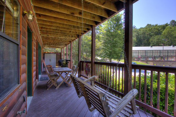 Swing and deck dining at Pool Side Lodge, a 6 bedroom cabin rental located in Pigeon Forge