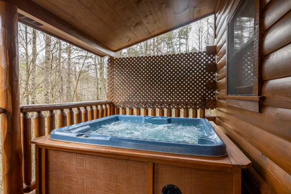 Hot tub on a covered porch with privacy fence at Whispering Grace, a 2 bedroom cabin rental located in Gatlinburg