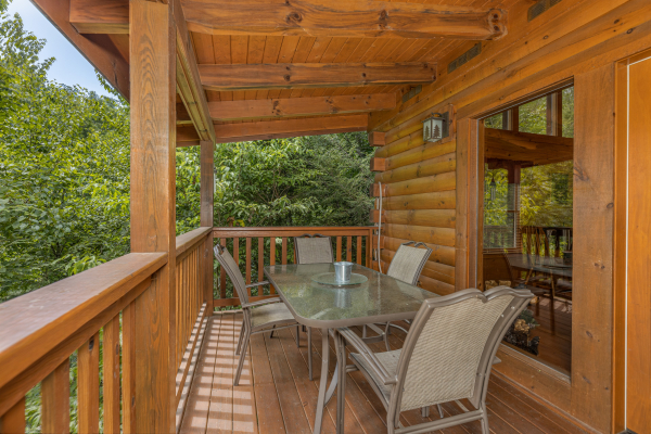 Outdoor dining for four on a covered deck at Cub's Crossing, a 3 bedroom cabin rental located in Gatlinburg