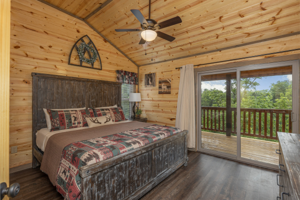 Bedroom with a king bed, night stand and lamp, and deck access at Alpine Adventure, a 4 bedroom cabin rental located in Pigeon Forge