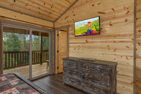 Dresser, TV, deck access, and en suite bath at Alpine Adventure, a 4 bedroom cabin rental located in Pigeon Forge