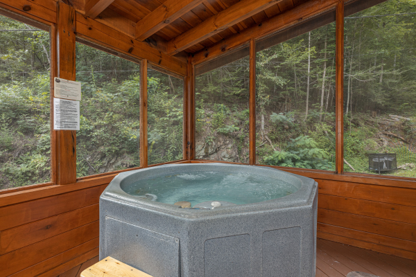 Hot tub on a screened in porch at King Wolf Lodge, a 3 bedroom cabin rental located in Pigeon Forge