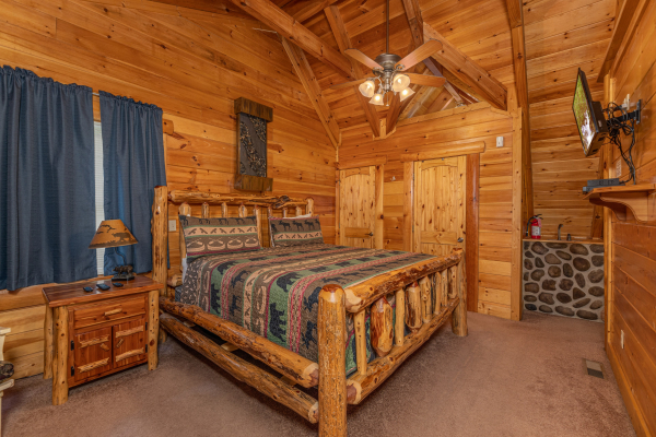 Bedroom with log bed, night stand, dresser, and TV at King Wolf Lodge, a 3 bedroom cabin rental located in Pigeon Forge