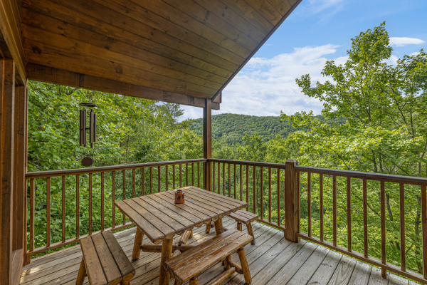 Dining area on a covered deck at Honeysuckle Hideaway, a 1 bedroom cabin rental located in Pigeon Forge