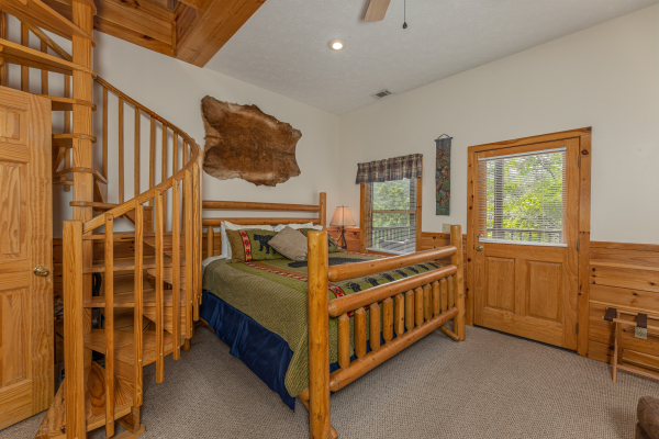 Bedroom with a spiral staircase and deck access at Honeysuckle Hideaway, a 1 bedroom cabin rental located in Pigeon Forge