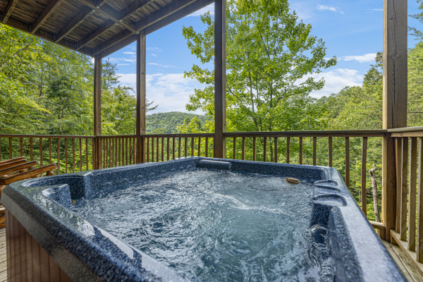 Hot tub on a covered deck at Honeysuckle Hideaway, a 1 bedroom cabin rental located in Pigeon Forge