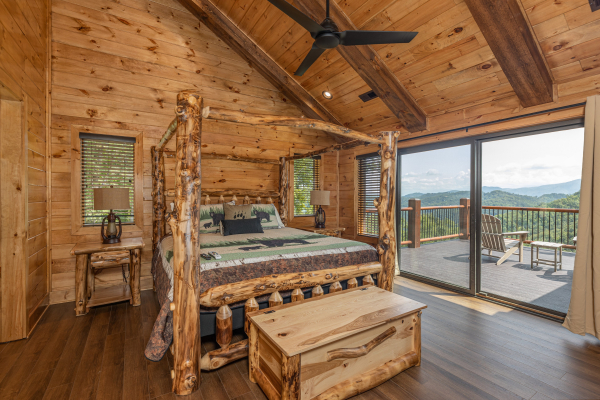 Four post log bed, night stands, lamps, chest, and deck access in a bedroom at Black Bears & Biscuits Lodge, a 6 bedroom cabin rental located in Pigeon Forge