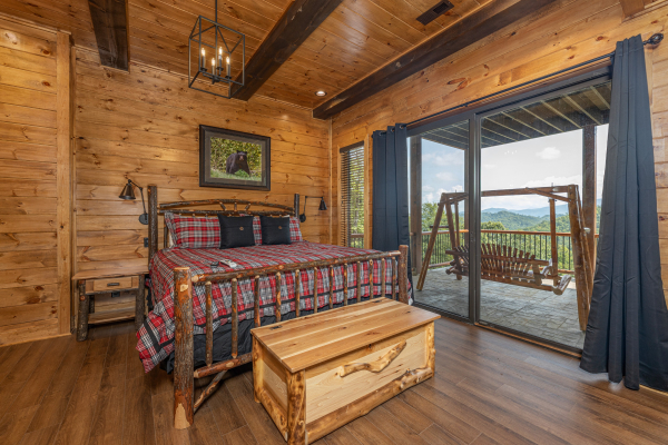 Bedroom with a log bed, night stand, trunk, and deck access at Black Bears & Biscuits Lodge, a 6 bedroom cabin rental located in Pigeon Forge