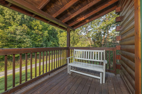 White bench on a covered deck at Family Getaway, a 4 bedroom cabin rental located in Pigeon Forge