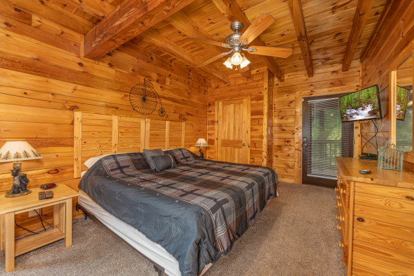 Bedroom with two night stands, lamps, dresser, TV, and deck access at Family Getaway, a 4 bedroom cabin rental located in Pigeon Forge
