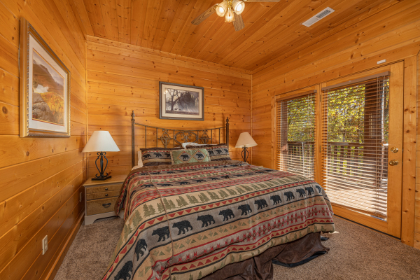Bedroom with queen bed, two night stands, and deck access at Grizzly's Den, a 5 bedroom cabin rental located in Gatlinburg