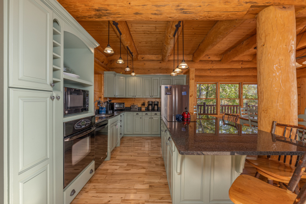 Kitchen with green cabinets and black appliances at Grizzly's Den, a 5 bedroom cabin rental located in Gatlinburg