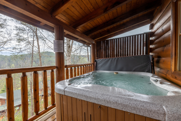 Hot tub on a covered deck at Absolutely Wonderful, a 2 bedroom cabin rental located in Pigeon Forge