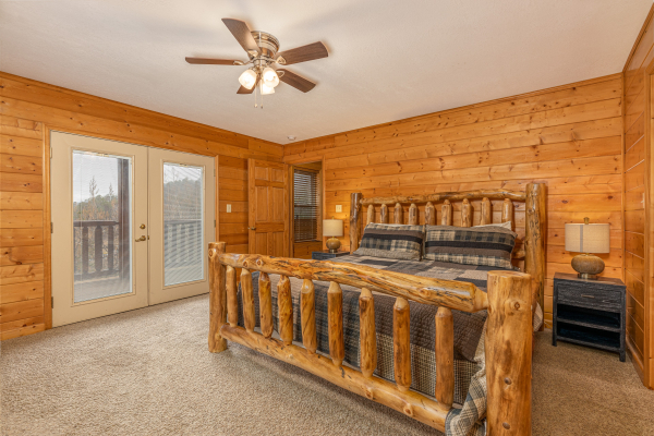 King log bed, two night stands, lamps, and deck access at Smoky Mountain Escape, a 3 bedroom cabin rental located in Pigeon Forge