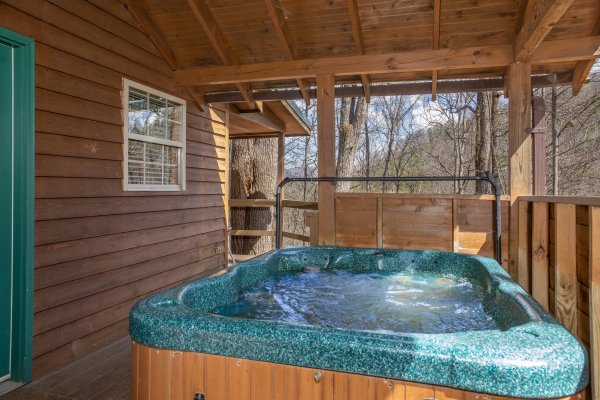 Hot tub on a covered deck at Hideaway, a 1 bedroom cabin rental located in Pigeon Forge