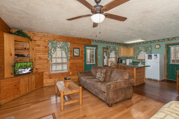 Living room with sofa, TV, and adjacent kitchen at Hideaway, a 1 bedroom cabin rental located in Pigeon Forge
