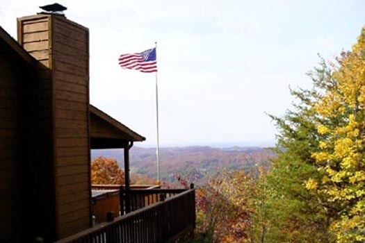 an american flag hangs high with a smoky mountain background at america's view a 2 bedroom cabin rental located in pigeon forge