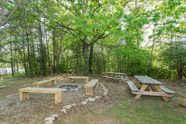 Fire pit with benches and picnic tables in the yard at Patriot Pointe, a 5 bedroom cabin rental located in Pigeon Forge