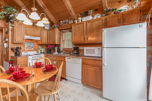Kitchen with white appliances and dining room for four Bare Hugs, a 1-bedroom cabin rental located in Pigeon Forge