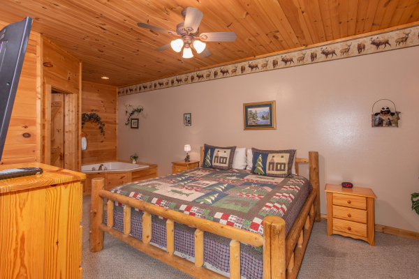 Bedroom with a king-sized log bed, jacuzzi, and dresser with television at Bearly in the Mountains, a 5-bedroom cabin rental located in Pigeon Forge