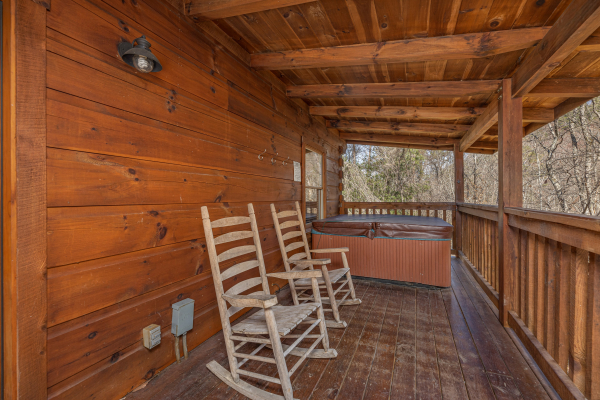 Porch with rocking chairs and hot tub at Smoky Bears Creek, a 2 bedroom cabin rental located in Pigeon Forge