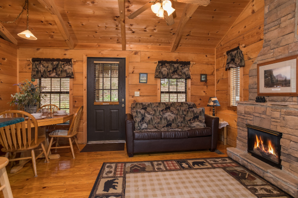Sofa, fireplace, and dining table in the living space at Boogie Bear, a 1-bedroom cabin rental located in Gatlinburg
