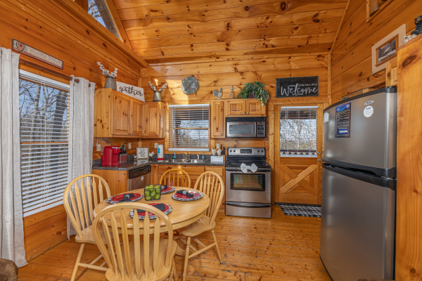 Dining table for four in a kitchen with stainless appliances at Honey Bear Haven, a 1 bedroom cabin rental located in Pigeon Forge