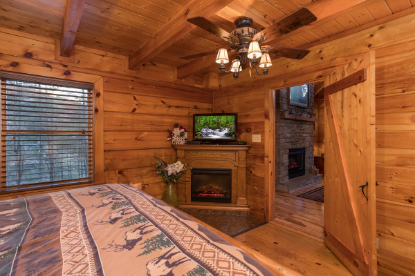 master bedroom with fireplace and television at always & forever a 1 bedroom cabin rental located in pigeon forge