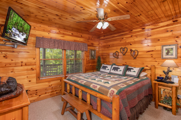 King-sized log bed with flat screen television at Bear Country, a 3-bedroom cabin rental located in Pigeon Forge