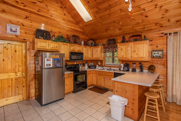 Kitchen with stainless appliances and counter seating for three at Bear Country, a 3-bedroom cabin rental located in Pigeon Forge