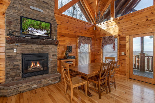 Fireplace with TV and dining set at 5 Star View, a 3 bedroom cabin rental located in Gatlinburg