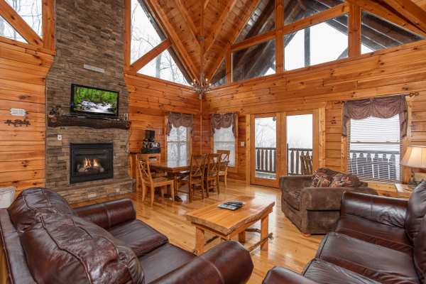Main floor living room, fireplace, TV, dining space, and deck access at 5 Star View, a 3 bedroom cabin rental located in Gatlinburg