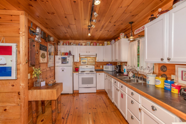 Kitchen with white cabinets and appliances at Aw Paw's Place, a 1-bedroom cabin rental located in Pigeon Forge