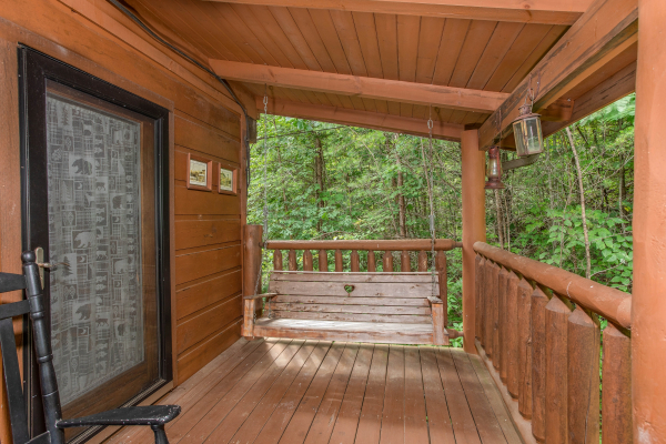 Porch swing on a covered deck at Aw Paw's Place, a 1-bedroom cabin rental located in Pigeon Forge