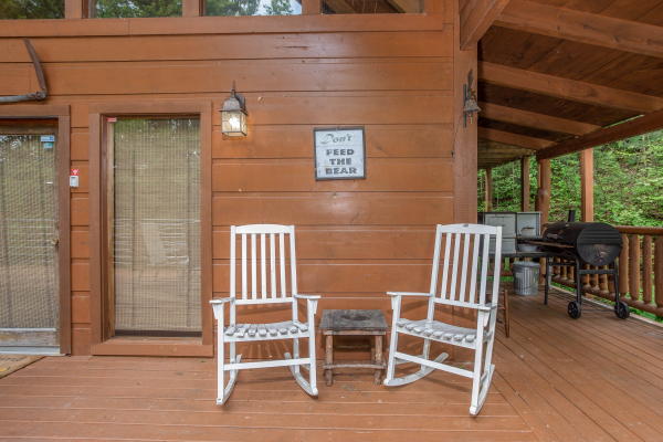 White rocking chairs on a covered deck at Aw Paw's Place, a 1-bedroom cabin rental located in Pigeon Forge