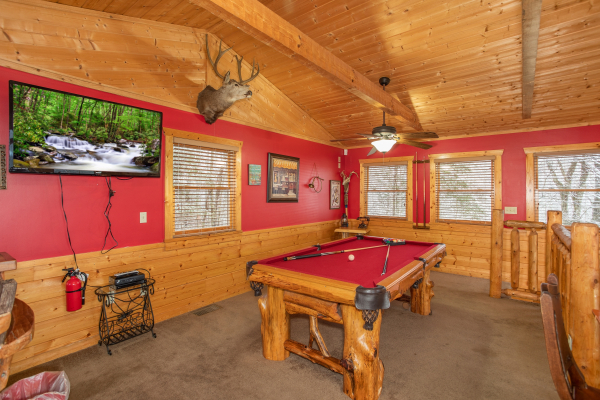 Red felt pool table and TV in the game loft at Alpine Romance, a 2 bedroom cabin rental located in Pigeon Forge